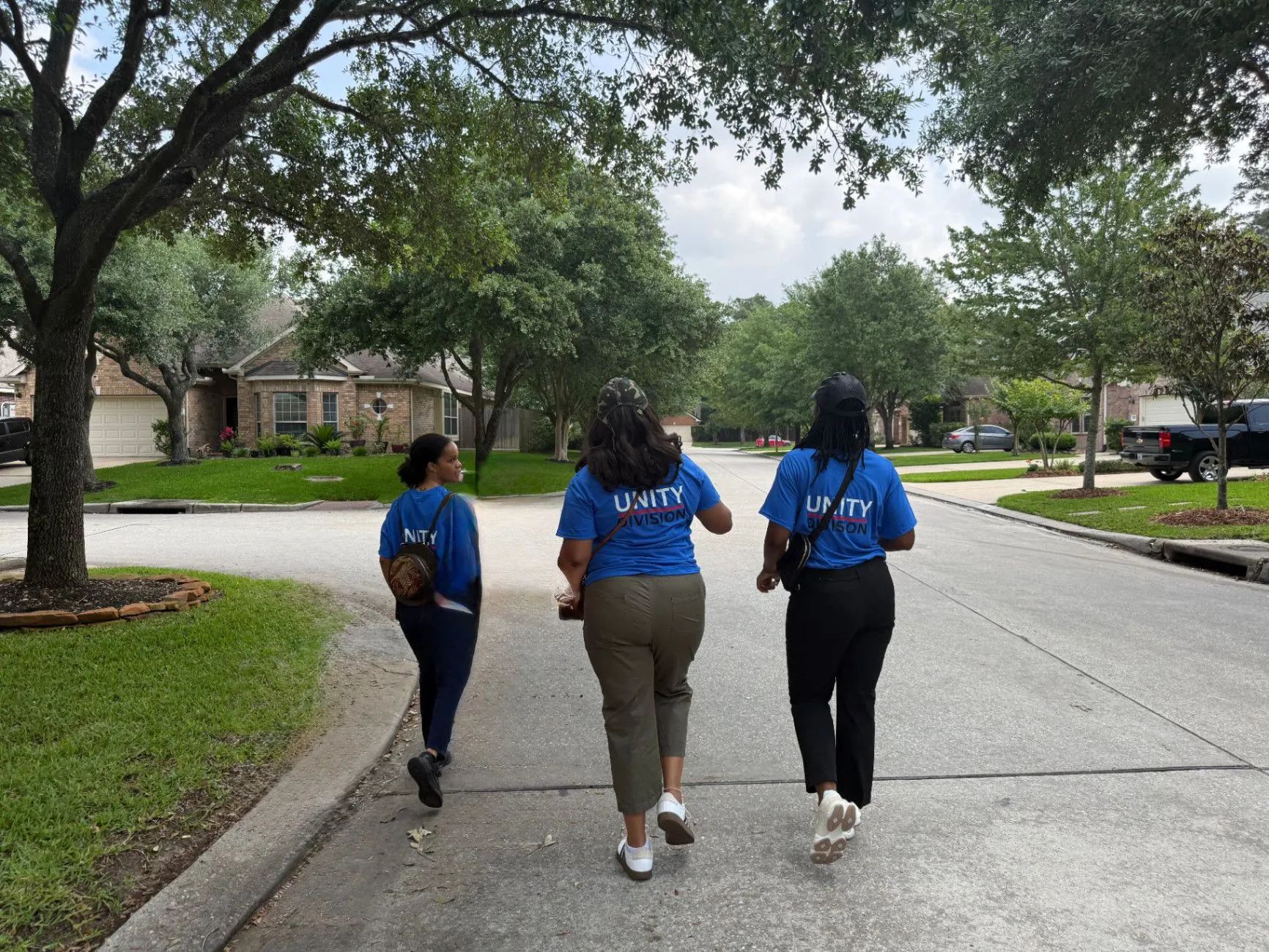Three volunteers walking together through a residential neighborhood
