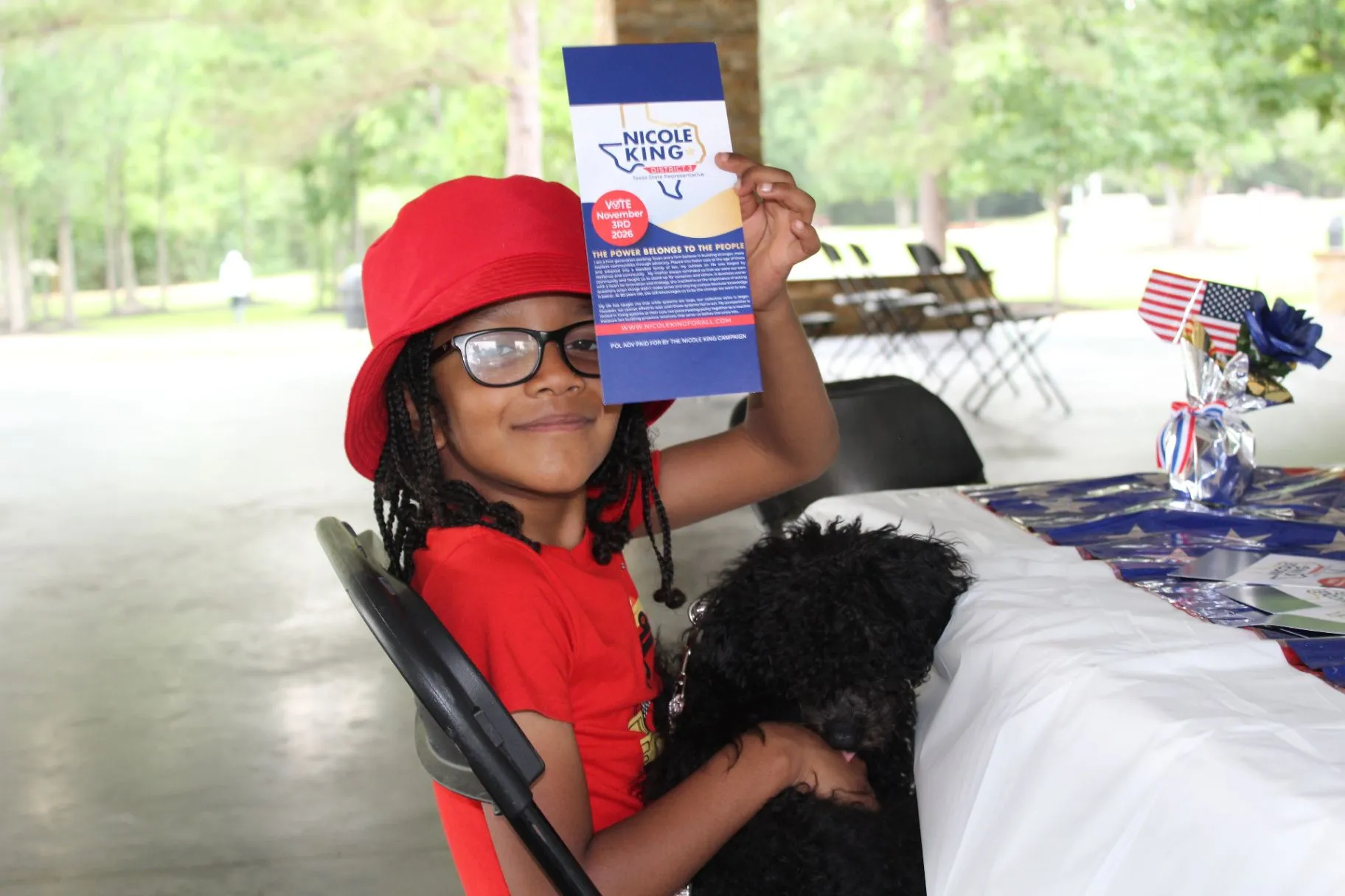 A young community member holding Nicole King campaign literature at a community event